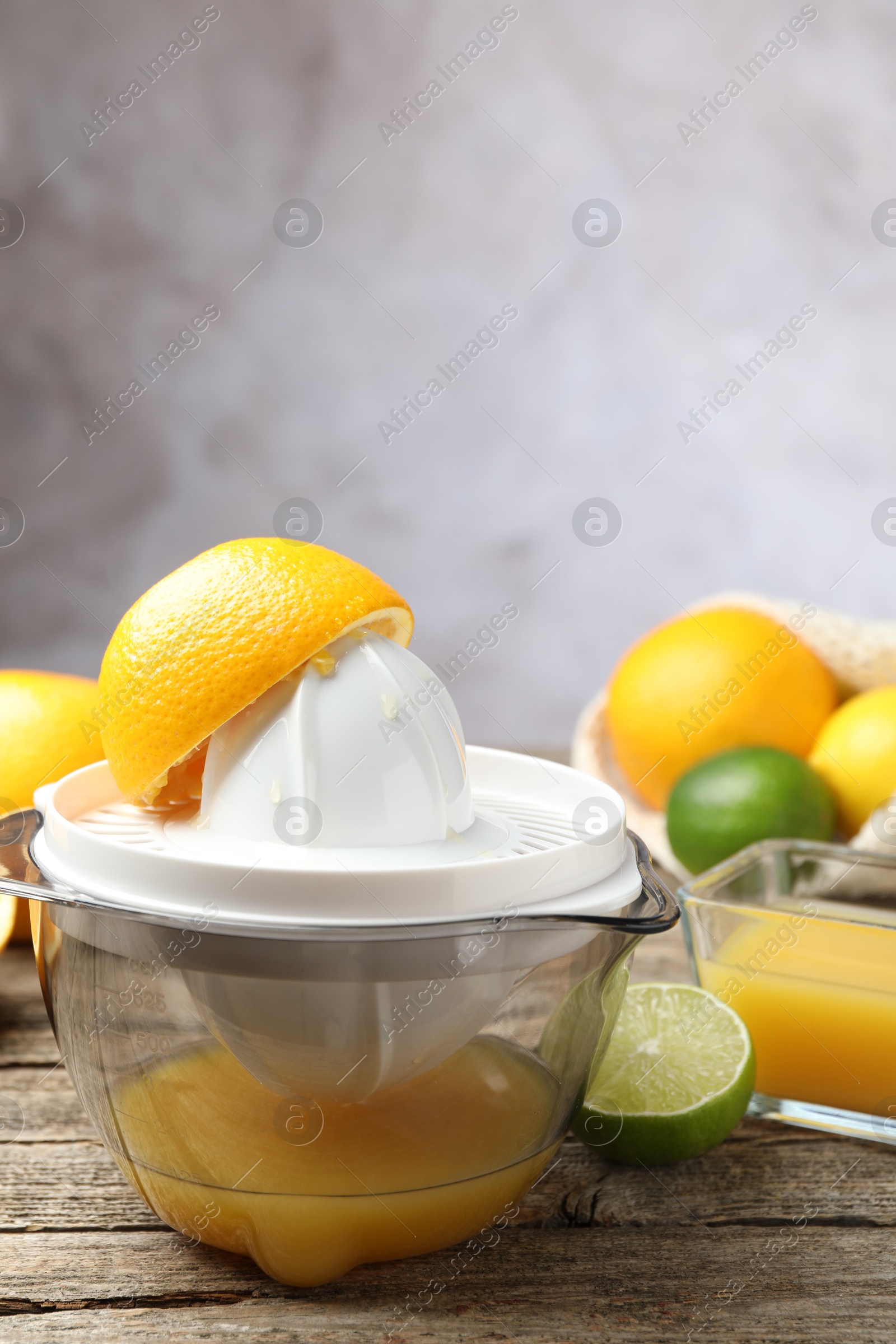 Photo of Plastic juicer and fresh oranges on wooden table, closeup