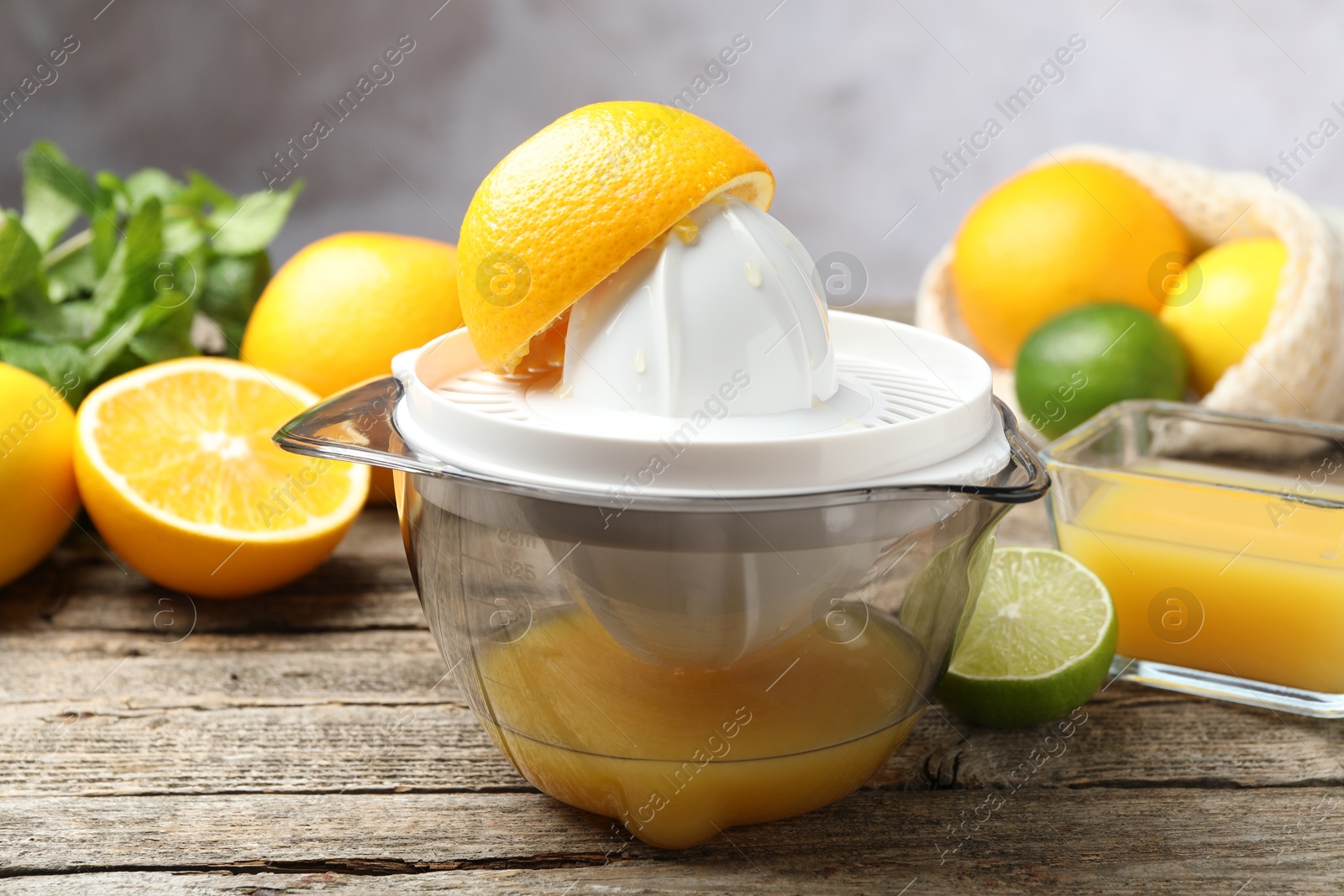 Photo of Plastic juicer and fresh oranges on wooden table, closeup