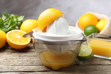 Photo of Plastic juicer and fresh oranges on wooden table, closeup