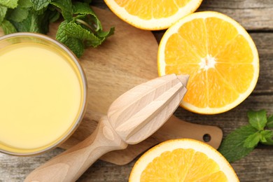 Photo of Juicer and fresh oranges on wooden table, flat lay