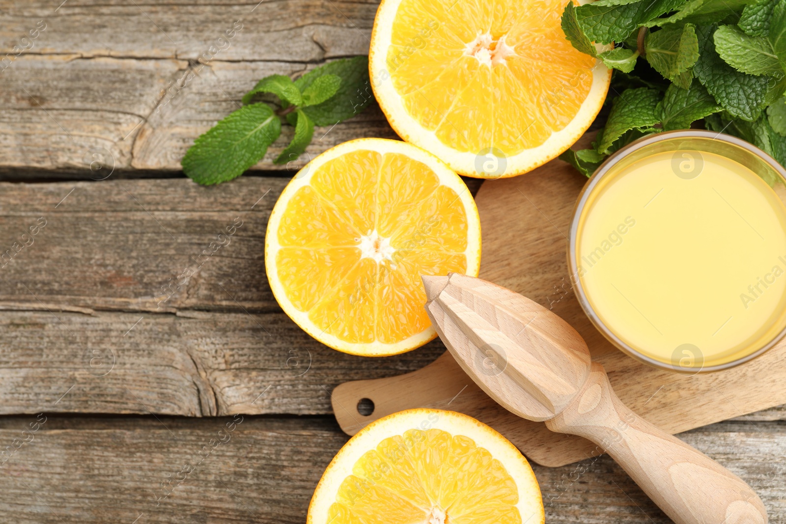 Photo of Juicer and fresh oranges on wooden table, flat lay. Space for text