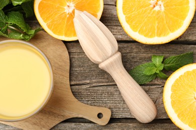 Photo of Juicer and fresh oranges on wooden table, flat lay