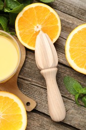 Juicer and fresh oranges on wooden table, flat lay