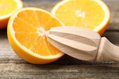 Photo of Juicer and fresh oranges on wooden table, closeup