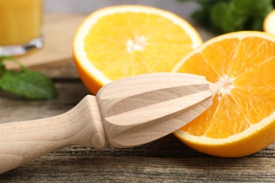 Photo of Juicer and fresh oranges on wooden table, closeup