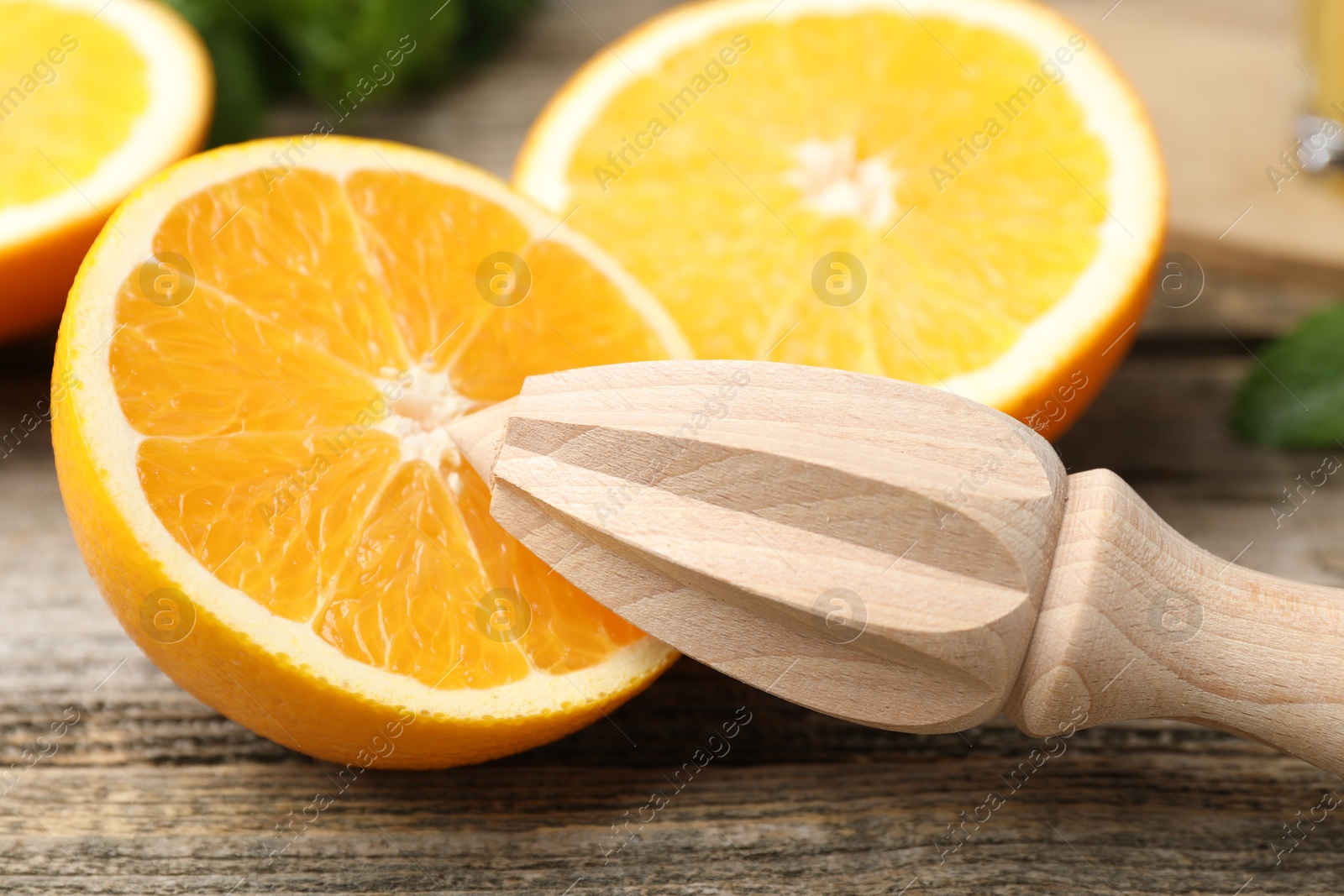 Photo of Juicer and fresh oranges on wooden table, closeup