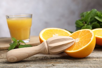 Photo of Juicer and fresh oranges on wooden table, closeup