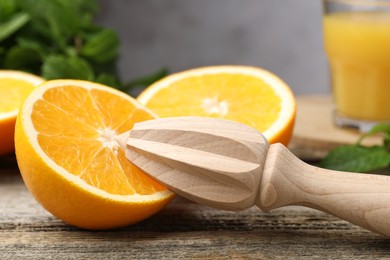 Photo of Juicer and fresh oranges on wooden table, closeup