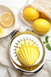 Plastic juicer and fresh lemons on white wooden table, flat lay