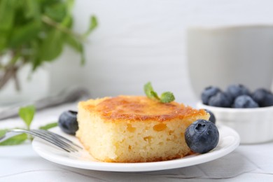 Photo of Slice of tasty semolina cake served on white textured table, closeup