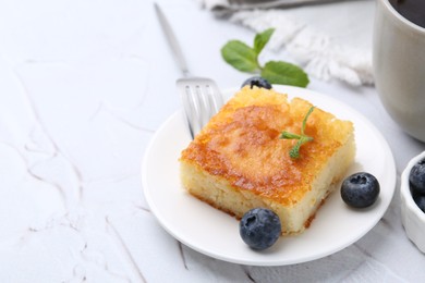 Photo of Slice of tasty semolina cake served on white textured table, closeup. Space for text