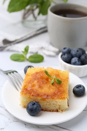 Photo of Slice of tasty semolina cake served on white textured table, closeup