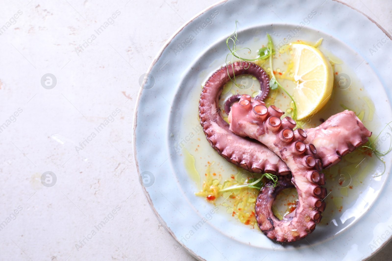 Photo of Appetizing octopus tentacles on light table, top view