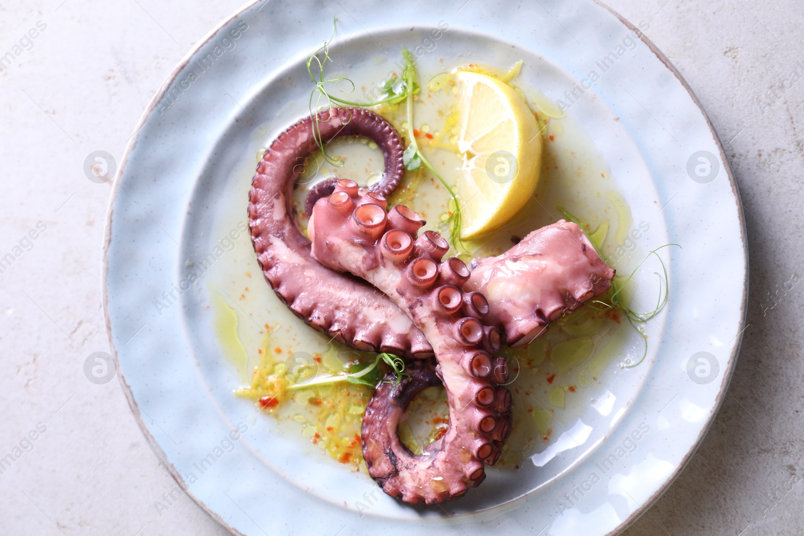 Photo of Appetizing octopus tentacles on light table, top view