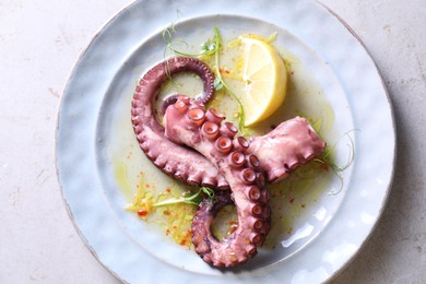 Photo of Appetizing octopus tentacles on light table, top view