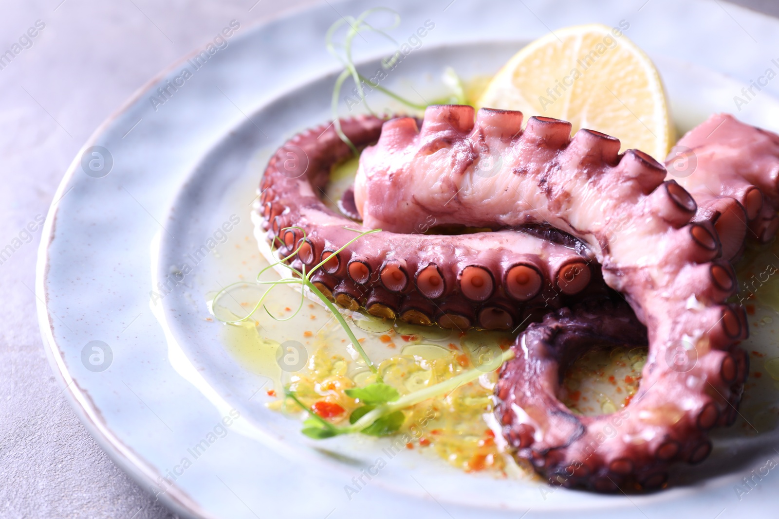 Photo of Appetizing octopus tentacles on light table, closeup