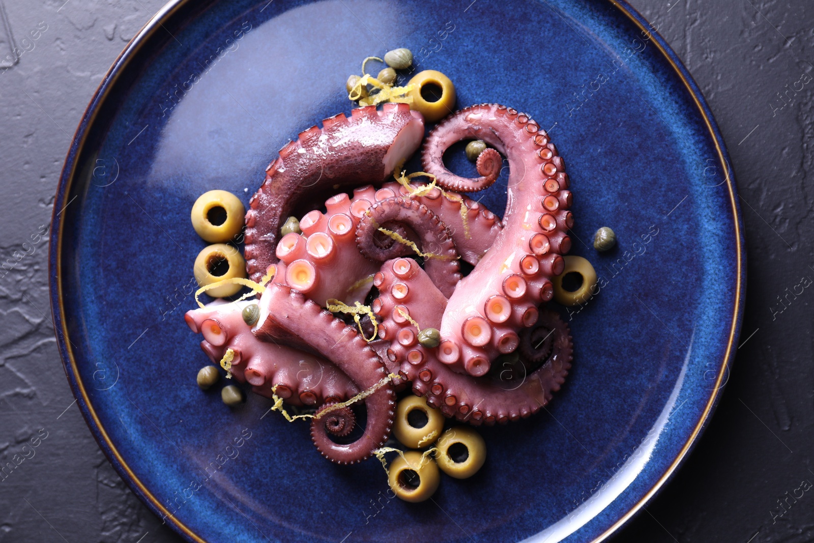 Photo of Appetizing octopus tentacles on dark table, top view