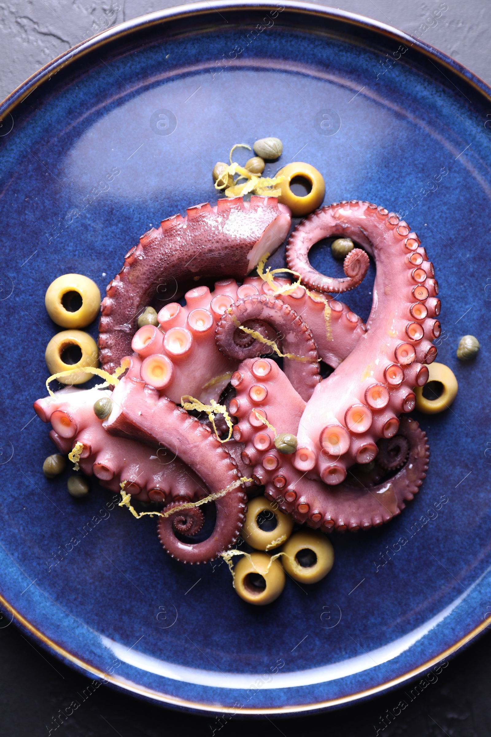 Photo of Appetizing octopus tentacles on dark table, top view