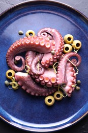 Photo of Appetizing octopus tentacles on dark table, top view