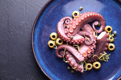 Photo of Appetizing octopus tentacles on dark table, top view