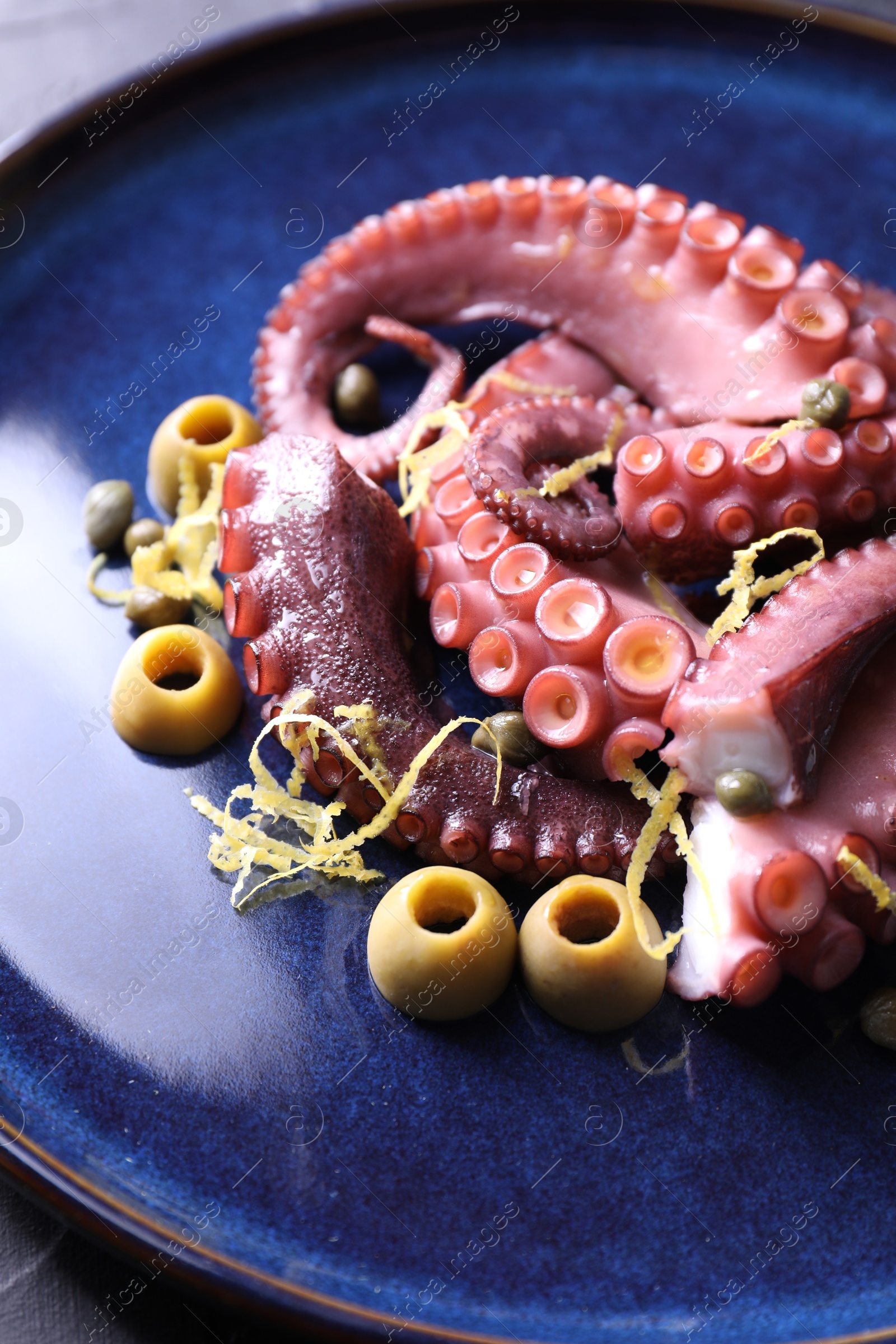 Photo of Appetizing octopus tentacles with olives on table, closeup