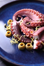 Photo of Appetizing octopus tentacles with olives on table, closeup