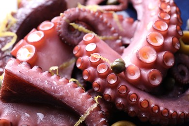 Photo of Appetizing octopus tentacles with lemon zest on plate, closeup