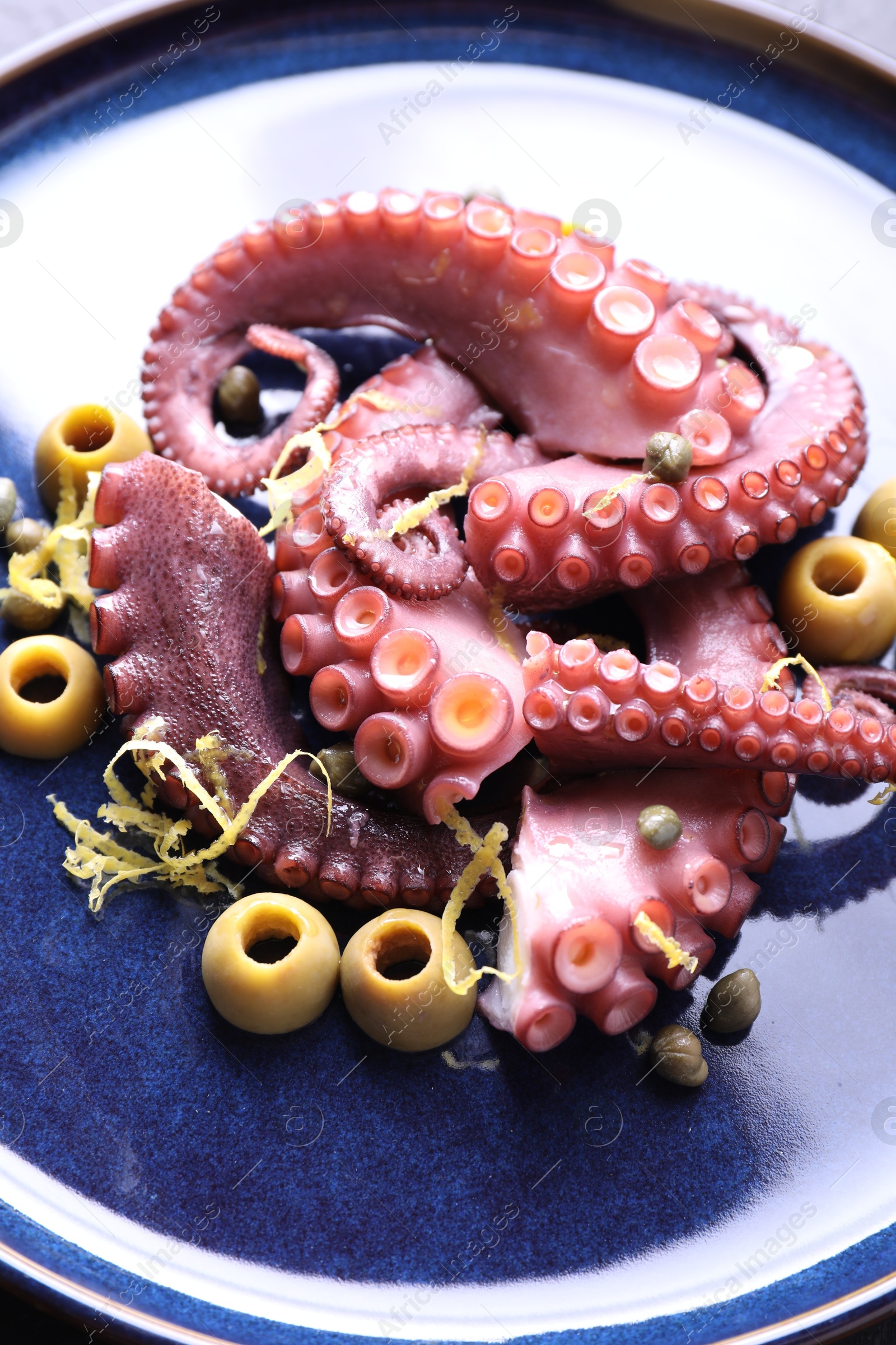 Photo of Appetizing octopus tentacles with olives on table, closeup