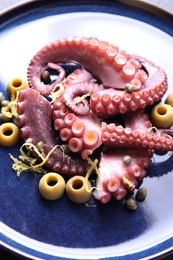 Photo of Appetizing octopus tentacles with olives on table, closeup