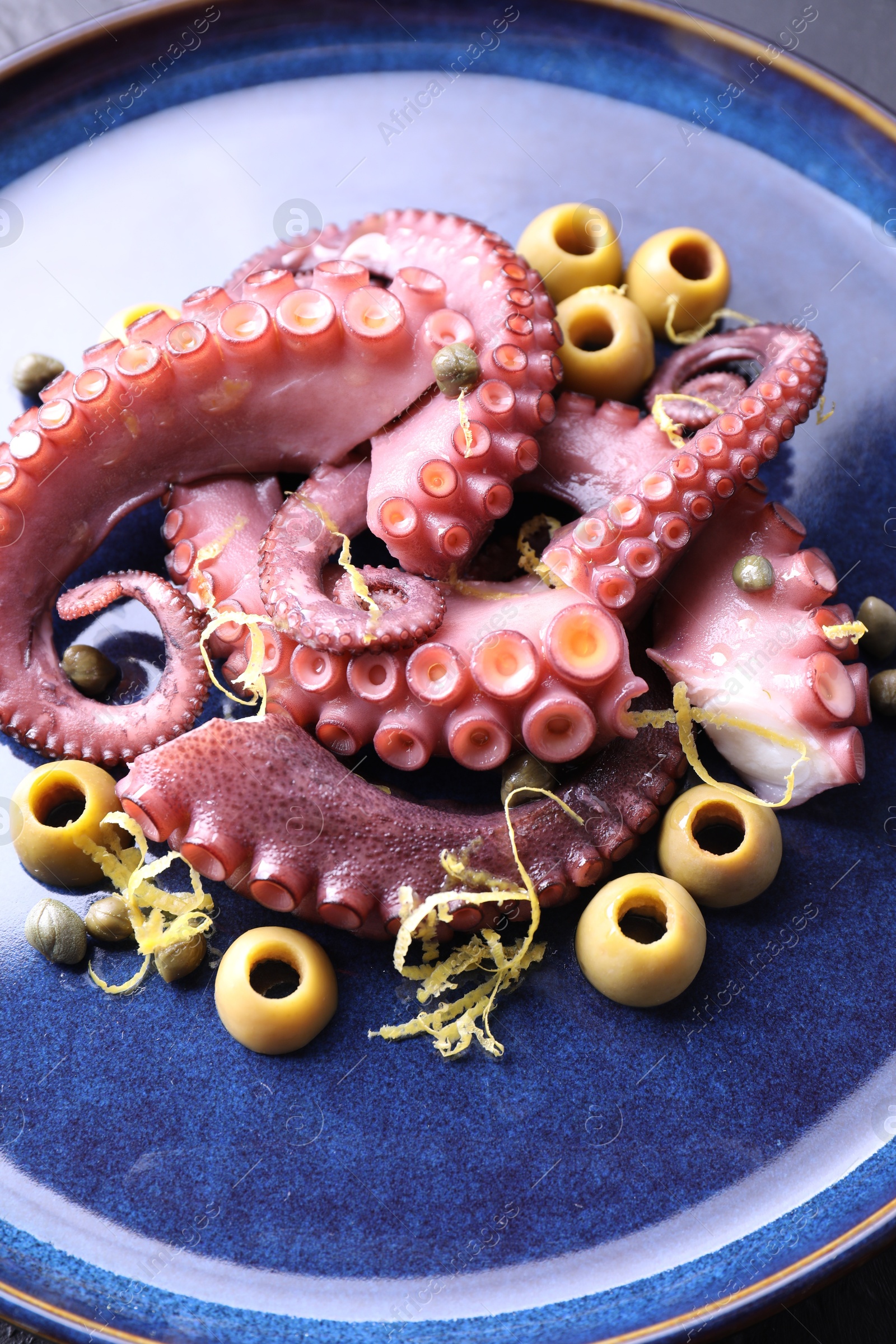 Photo of Appetizing octopus tentacles with olives on table, closeup