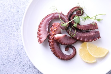 Photo of Appetizing octopus tentacles on grey table, top view