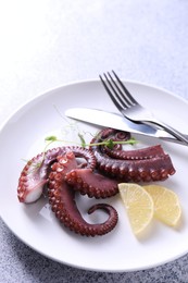 Appetizing octopus tentacles served on grey table, closeup