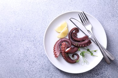 Photo of Appetizing octopus tentacles served on grey table, top view. Space for text