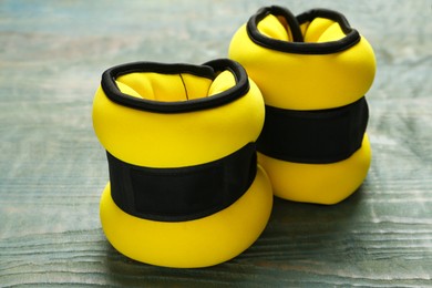 Photo of Yellow ankle weights on light blue wooden table