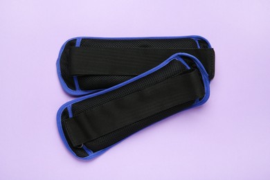 Photo of Blue ankle weights on violet background, flat lay