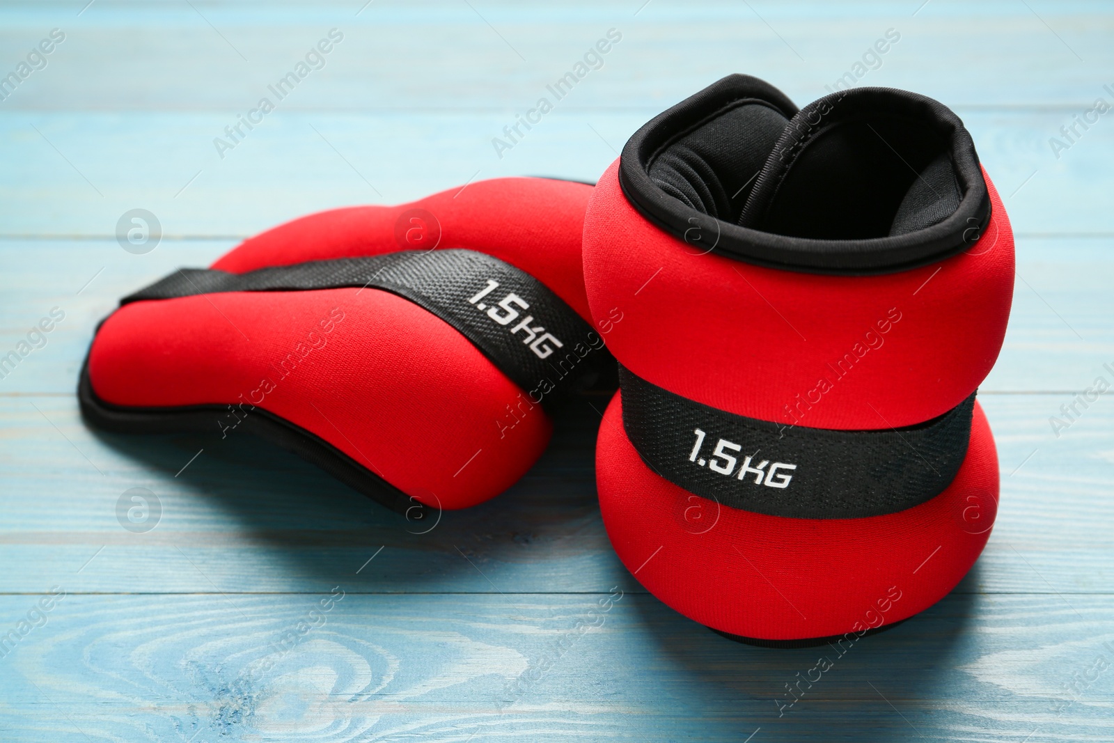 Photo of Stylish red ankle weights on turquoise wooden table