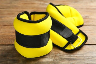 Stylish yellow ankle weights on wooden table