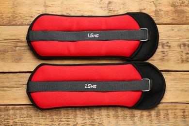 Photo of Red ankle weights on wooden table, flat lay