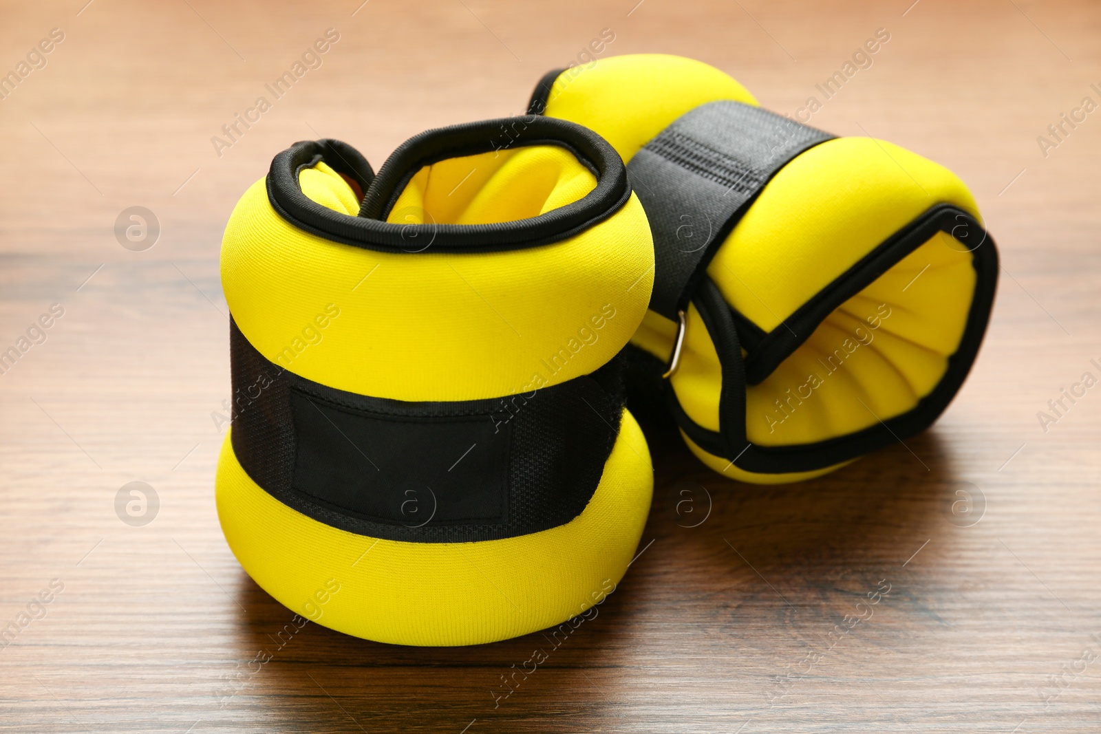 Photo of Stylish yellow ankle weights on wooden table