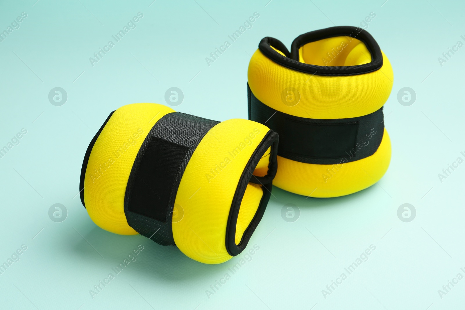 Photo of Stylish yellow ankle weights on turquoise background