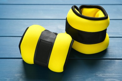 Yellow ankle weights on blue wooden table