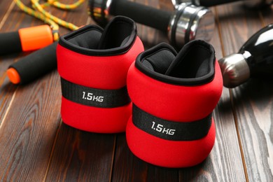 Photo of Red ankle weights and sport equipment on wooden table