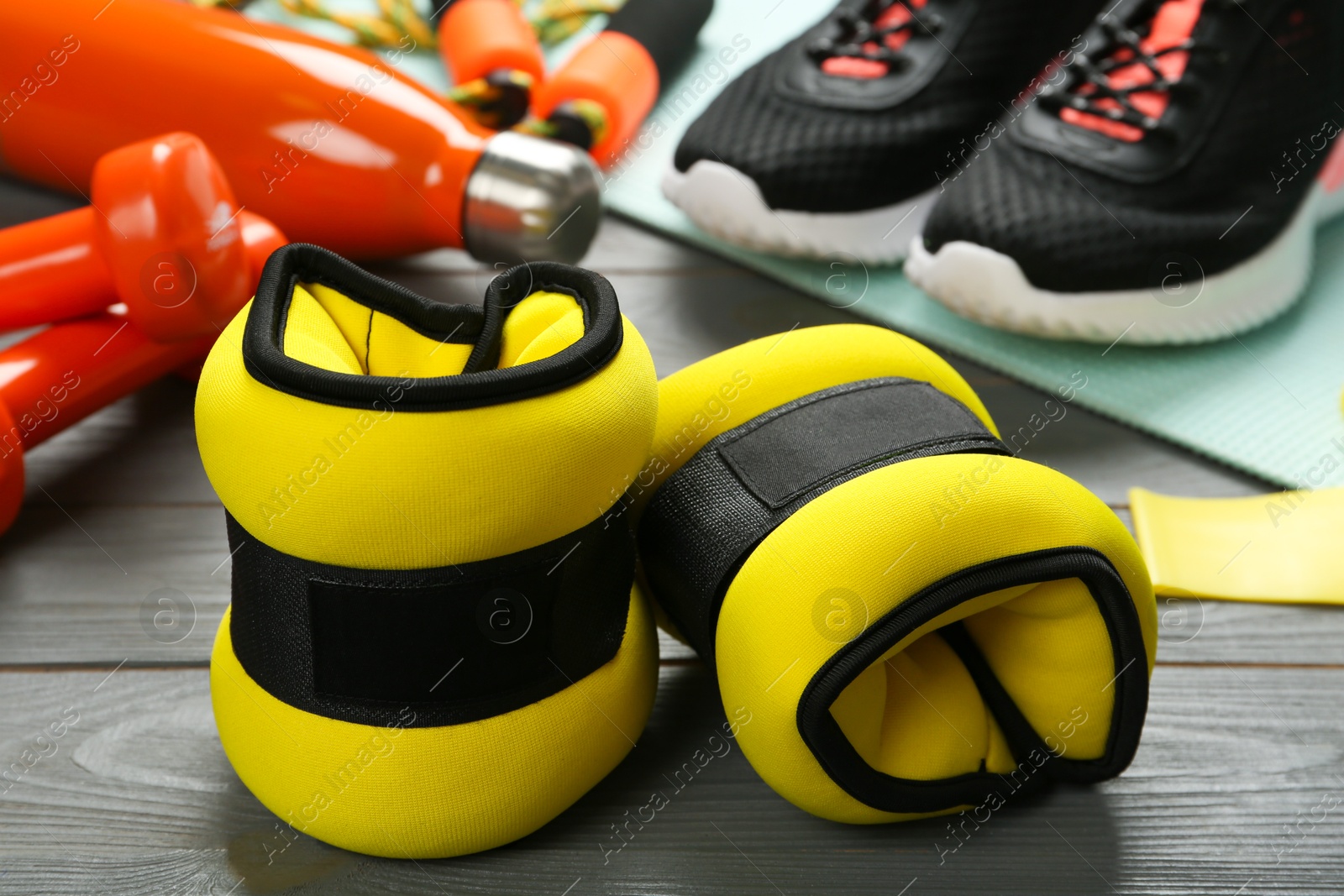 Photo of Yellow ankle weights and sport equipment on grey wooden table