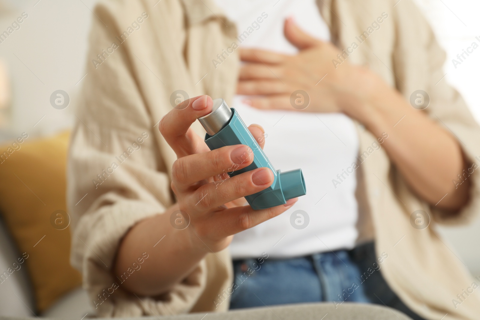 Photo of Woman holding inhaler indoors, closeup. Asthma treatment