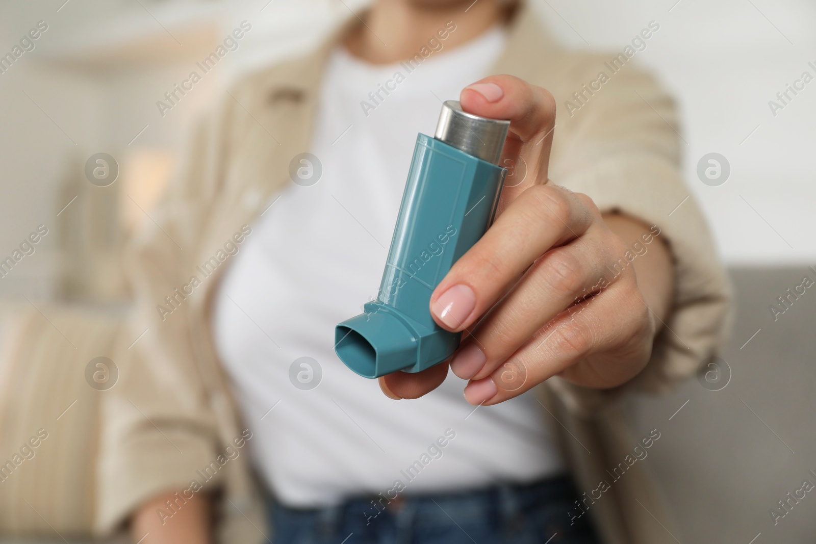 Photo of Woman holding inhaler indoors, closeup. Asthma treatment