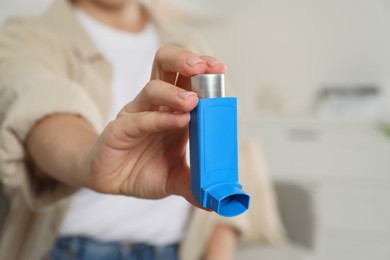 Photo of Woman holding inhaler indoors, closeup. Asthma treatment