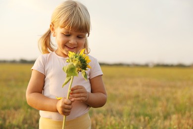 Photo of Cute little girl with sunflower at meadow. Child enjoying beautiful nature