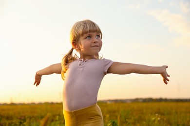 Photo of Cute little girl at meadow. Child enjoying beautiful nature