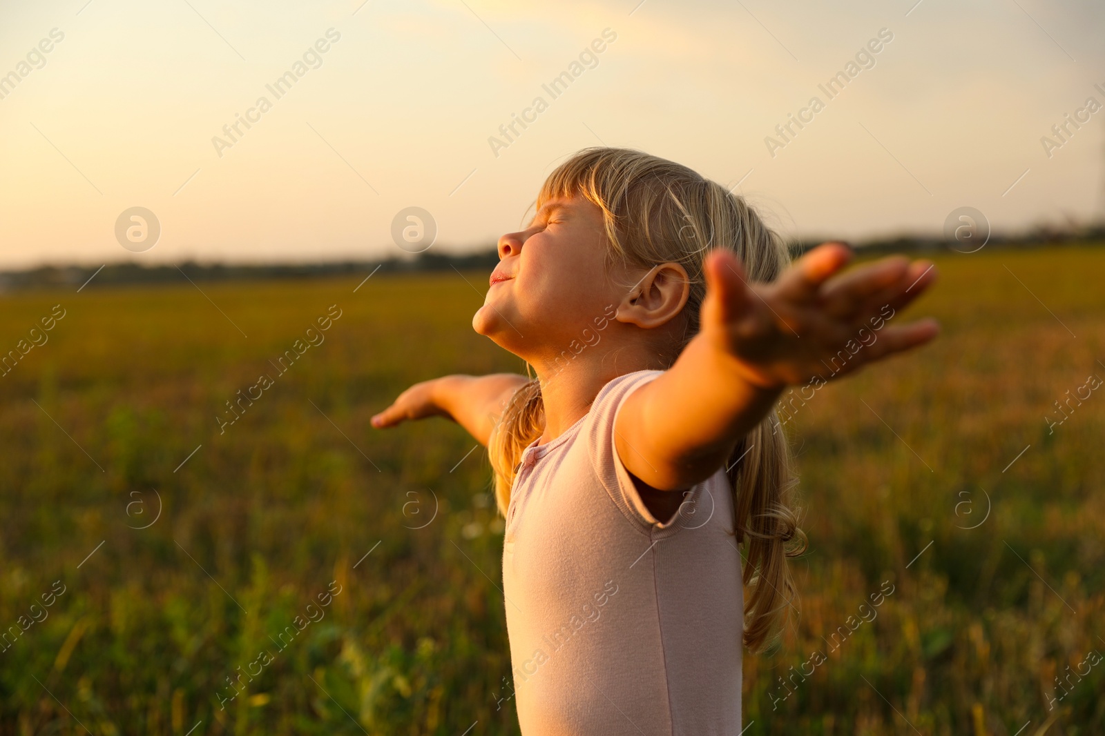 Photo of Cute little girl at meadow. Child enjoying beautiful nature