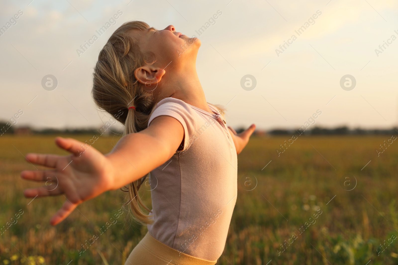 Photo of Cute little girl at meadow. Child enjoying beautiful nature